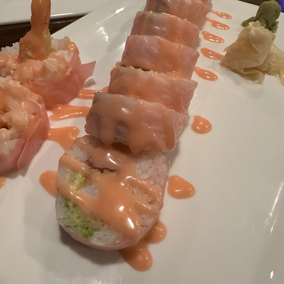 Inaka Sushi's sushi rolls with pink sauce, ginger, and wasabi on a white plate.